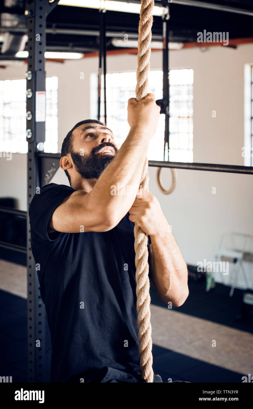 Determinato atleta maschio corda di arrampicata in palestra Foto Stock