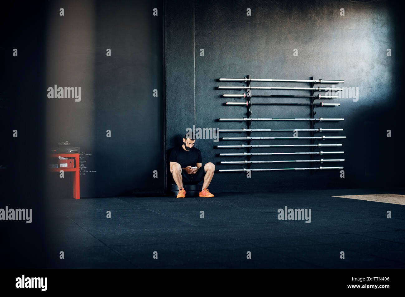 Atleta maschio utilizzando smart phone in palestra Foto Stock