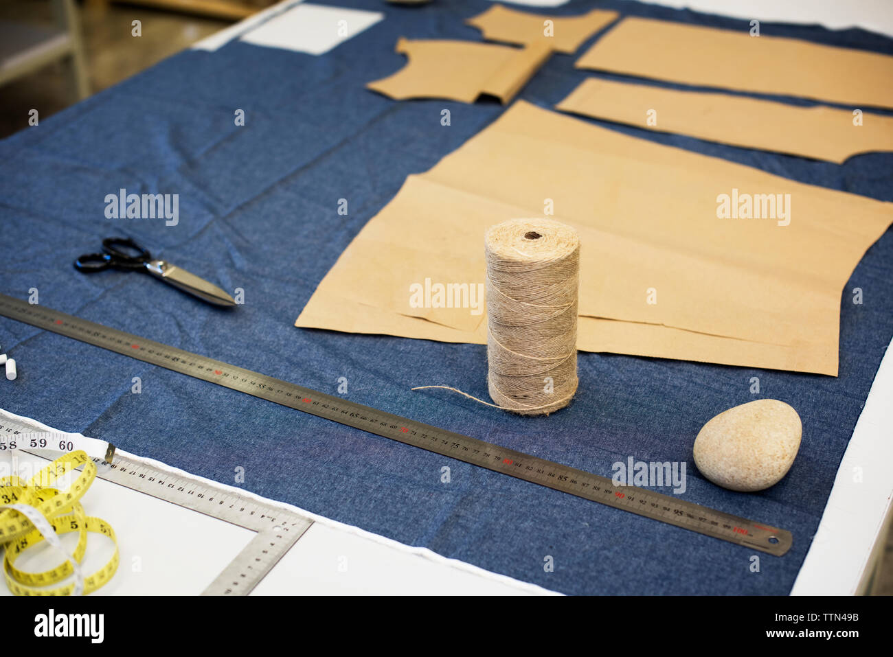 Angolo di alta vista di tessuto con filo di spool su tabella in officina Foto Stock