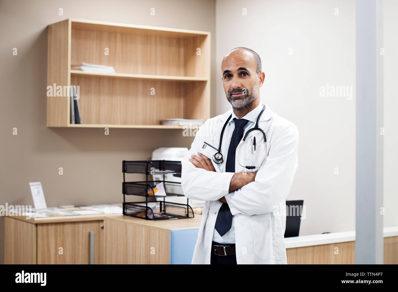 Ritratto di medico con le braccia incrociate in piedi in camera all'ospedale Foto Stock