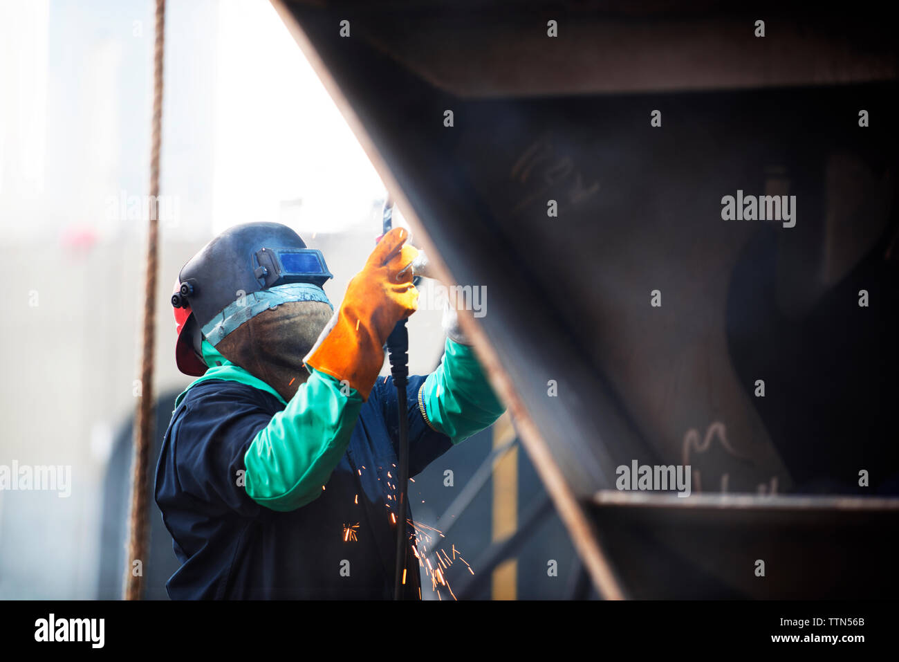 Lavoratore contenitore di saldatura nave presso l'industria Foto Stock