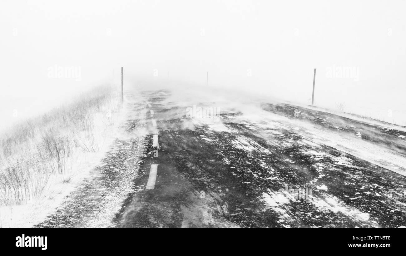 Coperta di neve strada durante la nebbia meteo Foto Stock