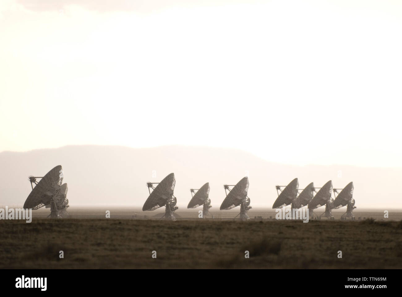 Parabola satellitare sul campo contro il cielo durante la nebbia meteo Foto Stock