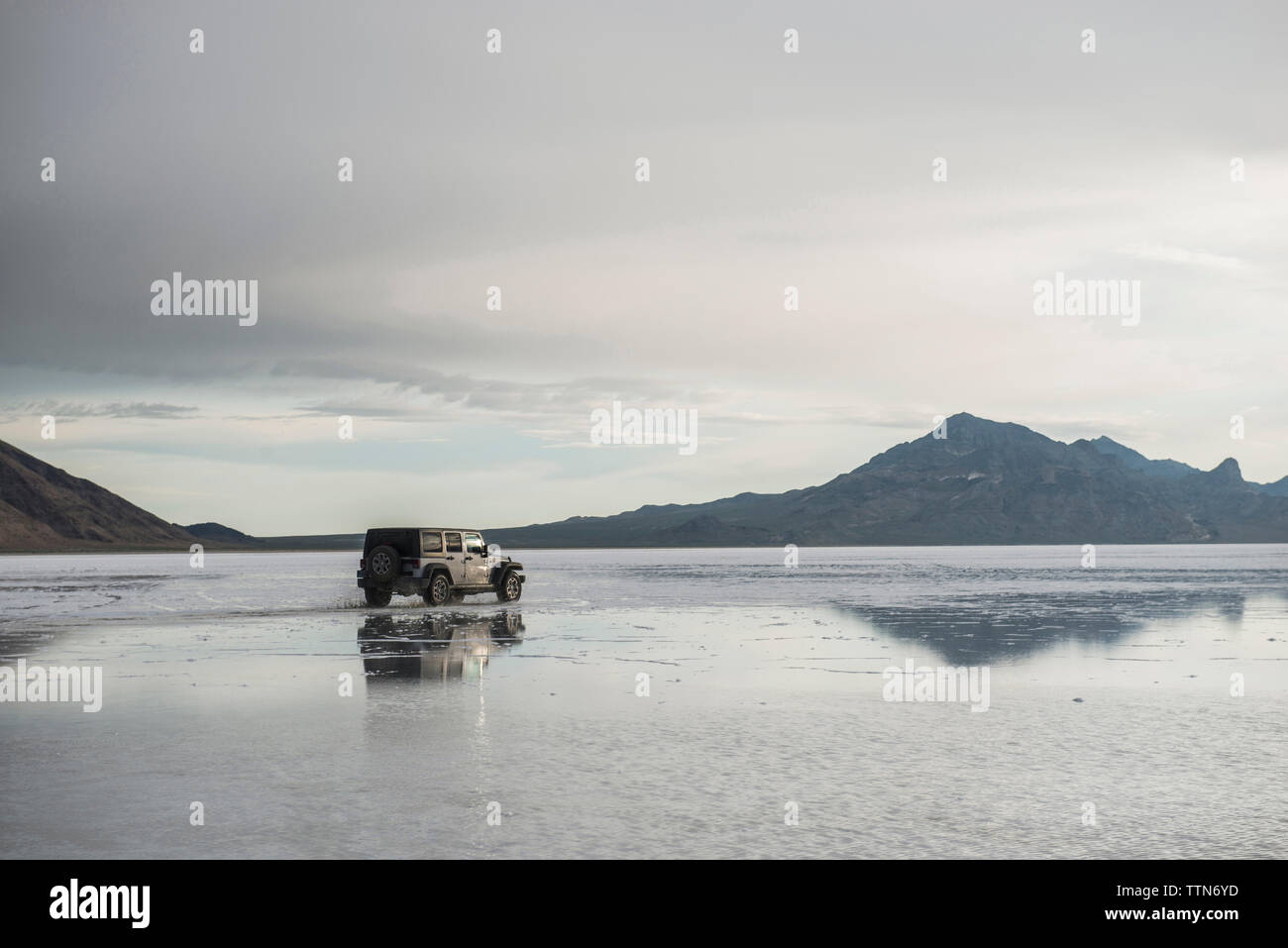 Sport Utility Vehicle a Bonneville Saline contro le montagne e il cielo Foto Stock