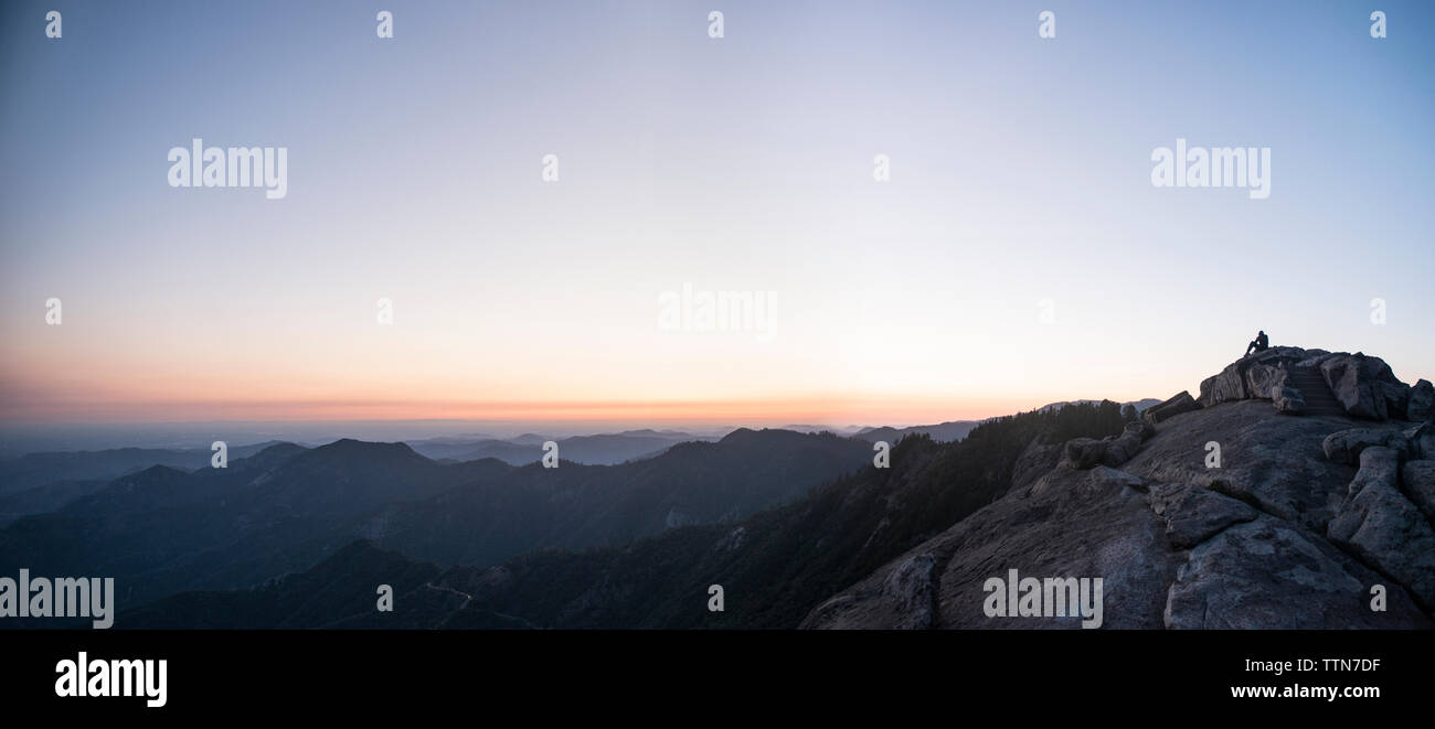 Vista in lontananza uomo seduto sulla scogliera a sequoia national park contro il cielo durante il tramonto Foto Stock