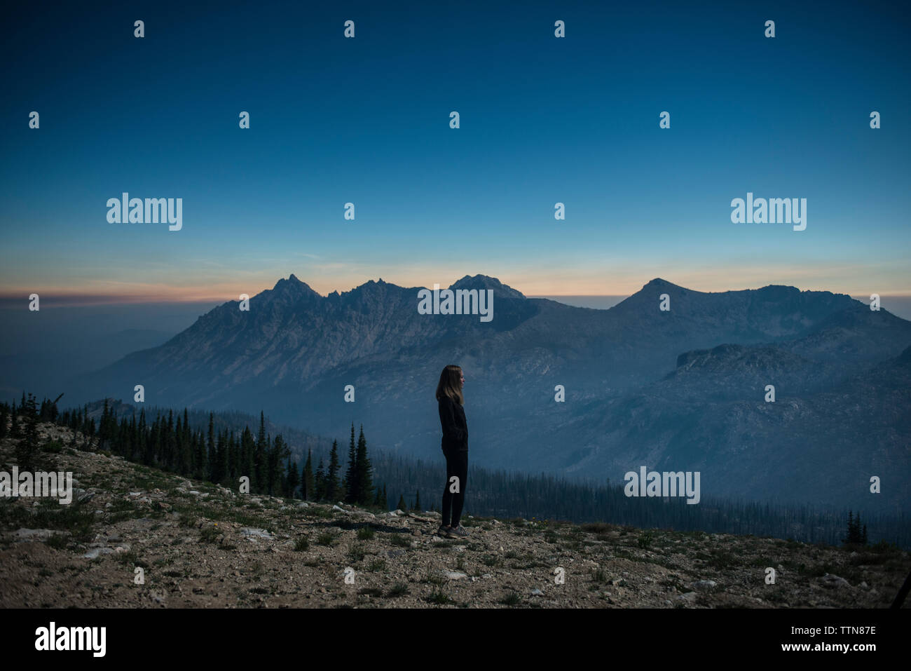 Vista laterale della donna in piedi sulla scogliera alla gamma a dente di sega Foto Stock
