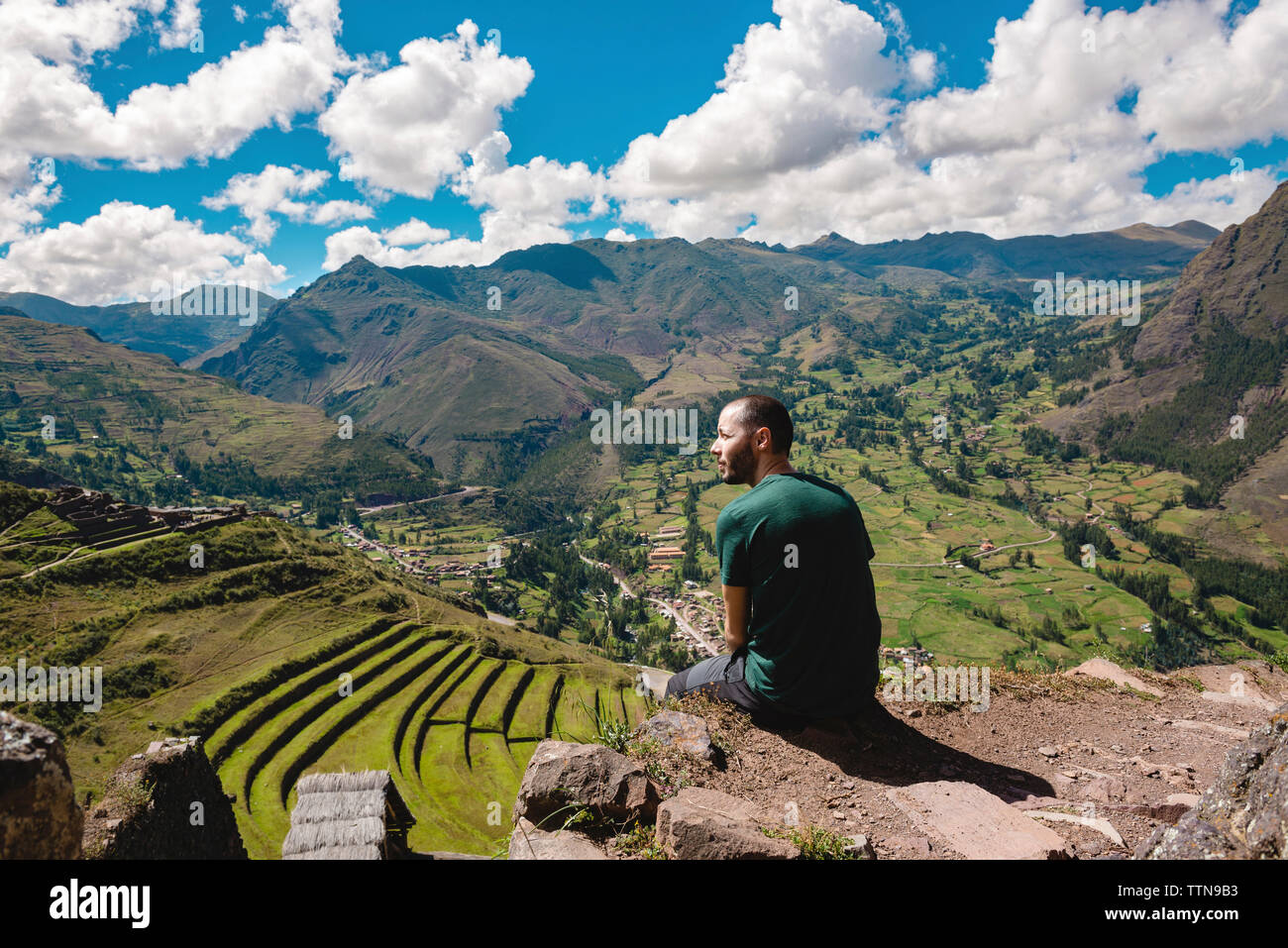 Vista posteriore di un escursionista guardando a vista mentre si è seduti sulla montagna contro il cielo di Pisac Foto Stock