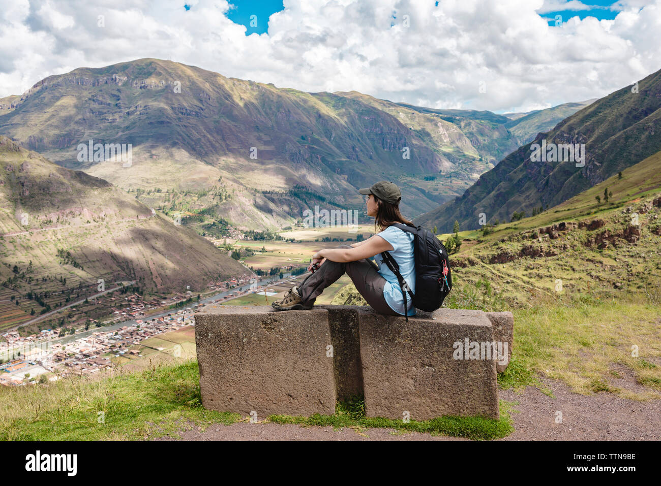 Vista laterale della donna con zaino seduti sulla montagna contro il cielo nuvoloso di Pisac Foto Stock