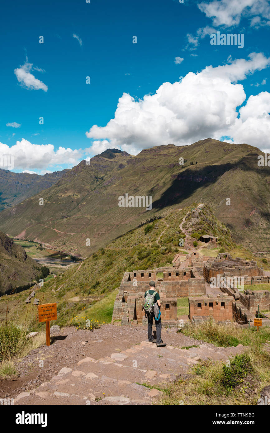 Vista posteriore di un escursionista guardando vecchi ruderi mentre si sta in piedi sul monte contro il cielo di Pisac Foto Stock