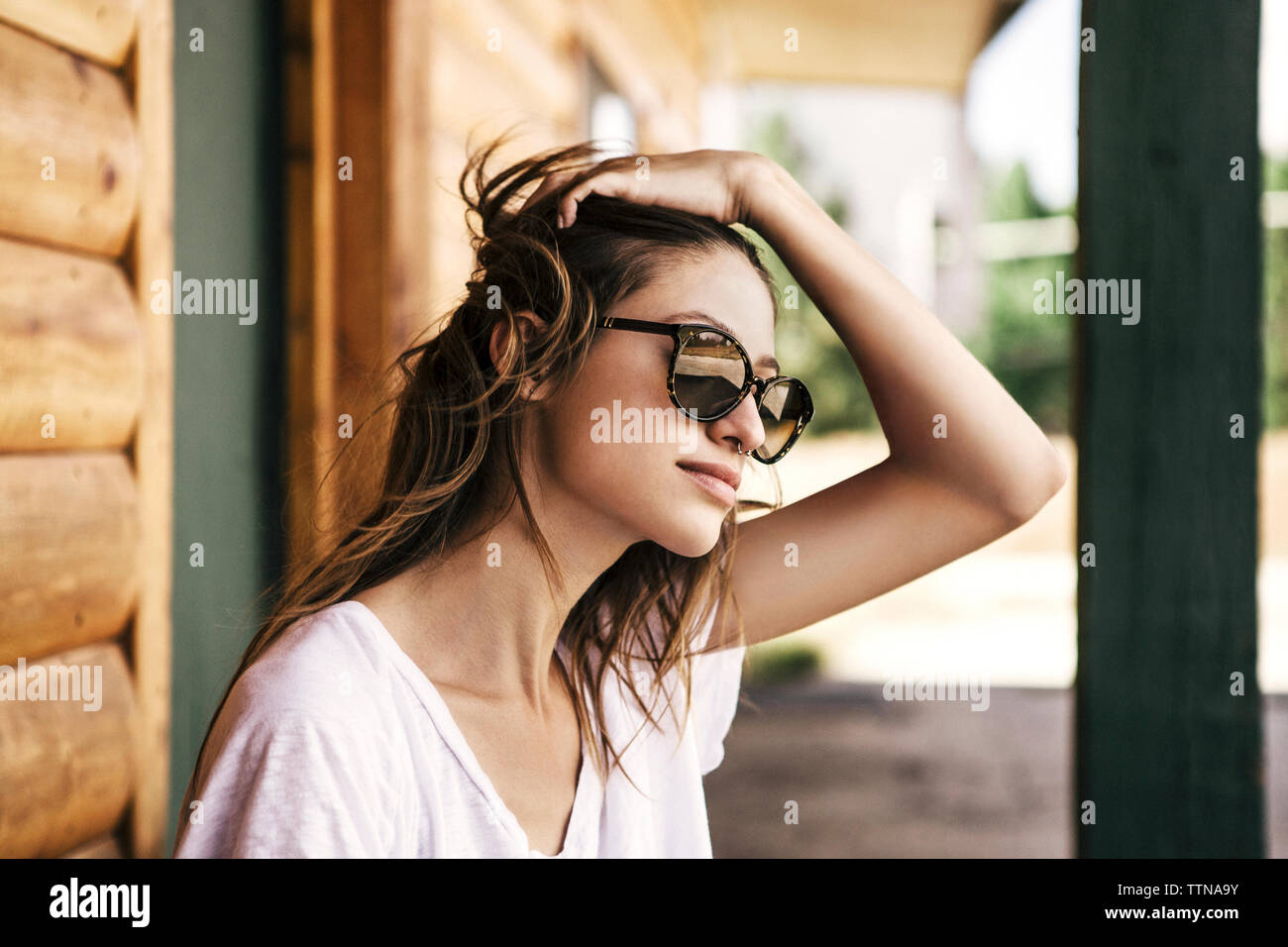 Bella donna con le mani nei capelli al di fuori di log cabin durante le vacanze Foto Stock