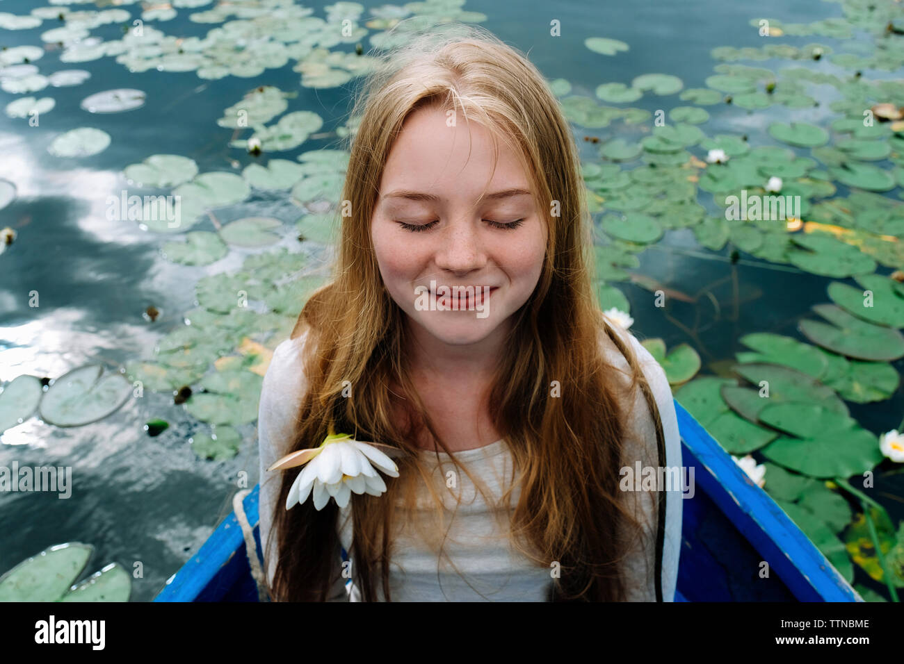 Close-up di donna felice con gli occhi chiusi seduti in barca sul lago Foto Stock