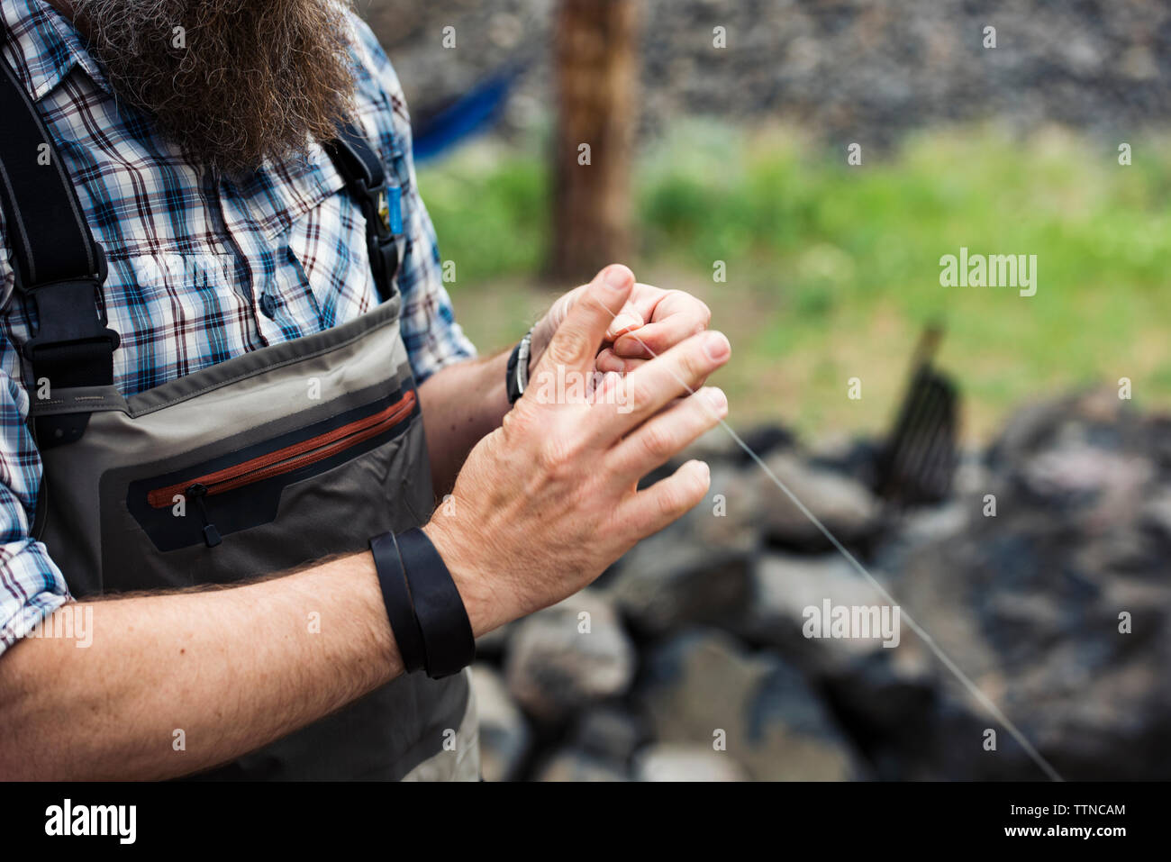 Sezione mediana di uomo maturo tenendo la pesca thread sul campo Foto Stock