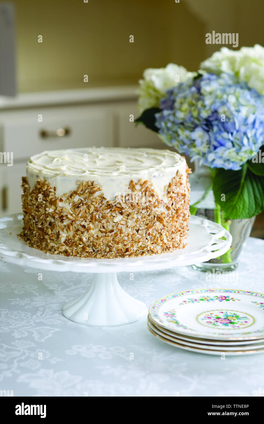 Torta di crema italiana con vaso di fiori sul tavolo a casa Foto Stock