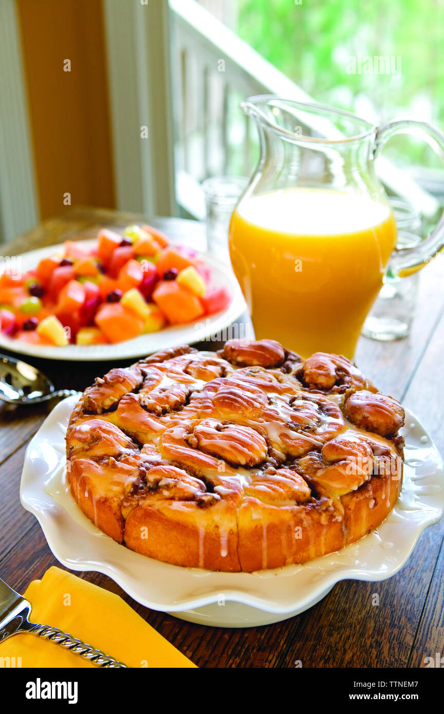 Primo piano di pasticceria cotta con succo d'arancia e Macedonia di frutta sul tavolo a casa Foto Stock