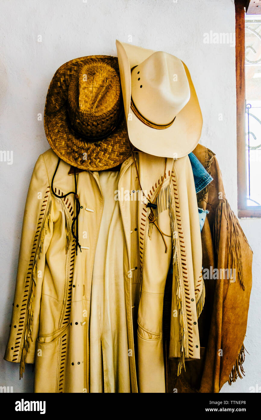 Cappelli da cowboy con i cappotti appesi sulla parete Foto Stock