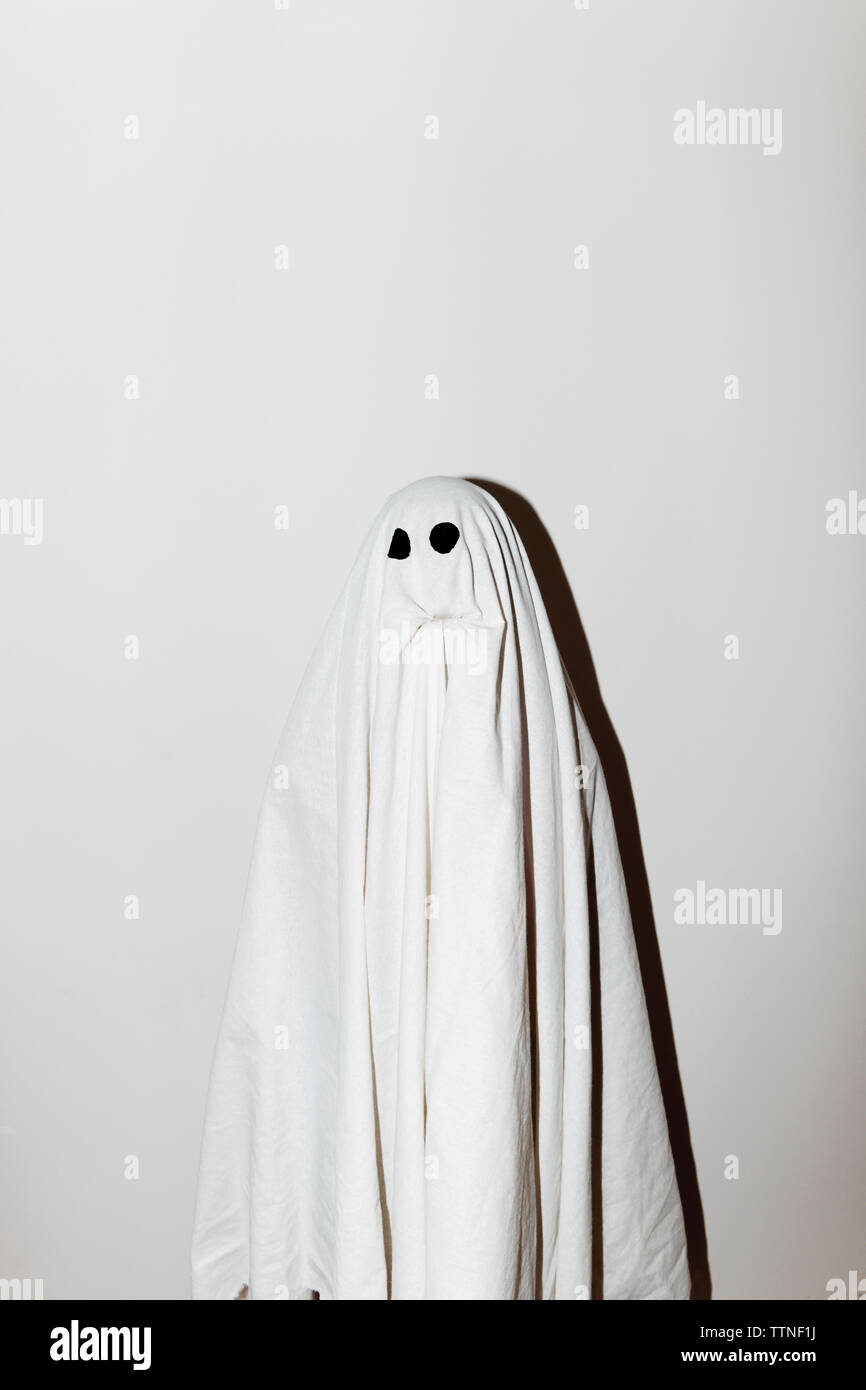 Uomo in costume fantasma in piedi contro la parete Foto Stock