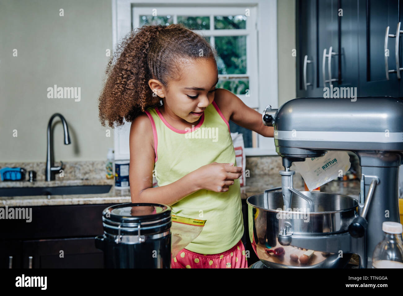 Ragazza utilizzando sbattere la macchina in cucina Foto Stock