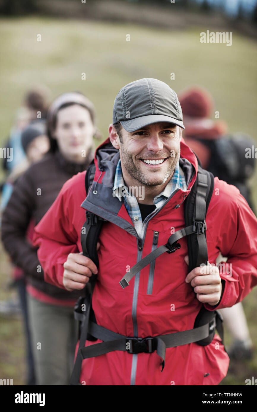Felice escursionista che porta uno zaino con gli amici in background Foto Stock