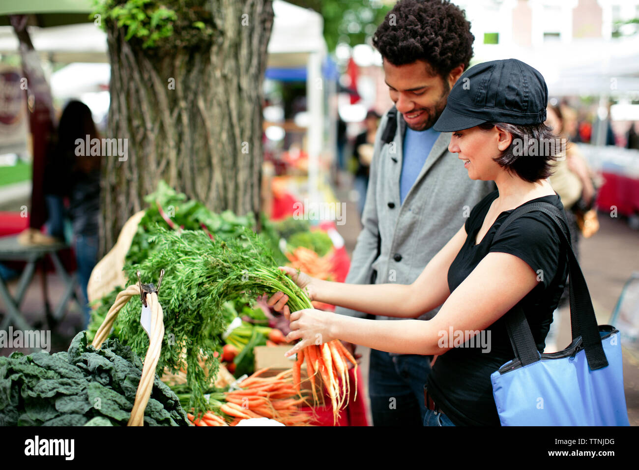 Multi-etnico giovane acquistare verdure in stallo del mercato Foto Stock