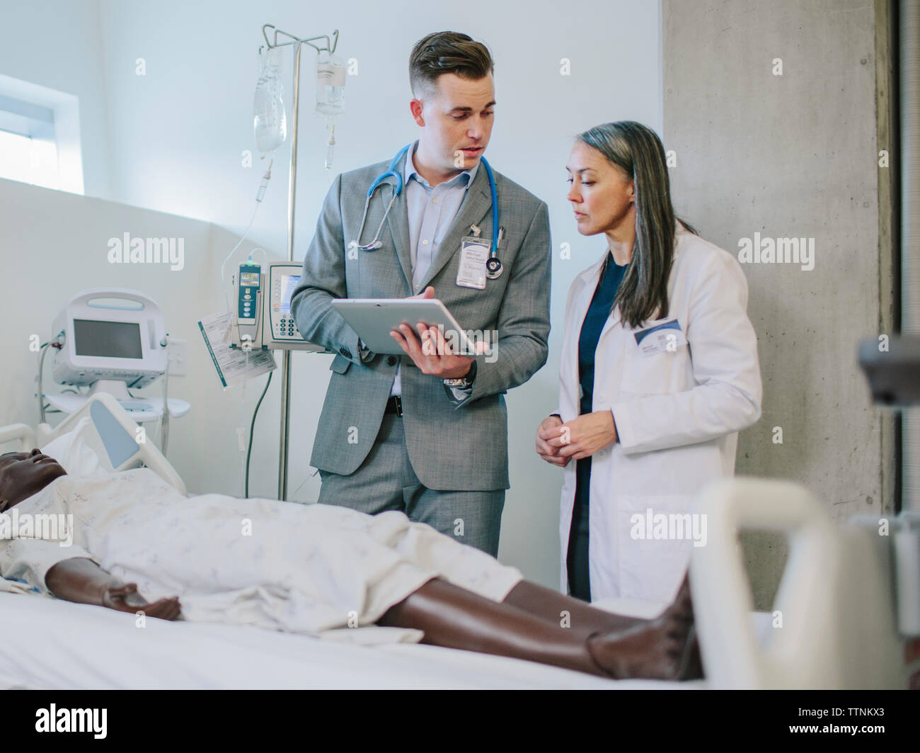 Medico maschio a discutere con il collega femmina su tablet computer nella scuola medica Foto Stock