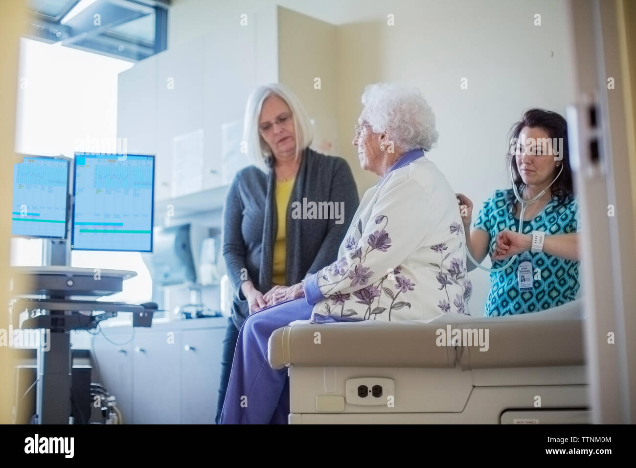 Figlia guardando medico donna madre di ascolto di respirazione in ospedale Foto Stock