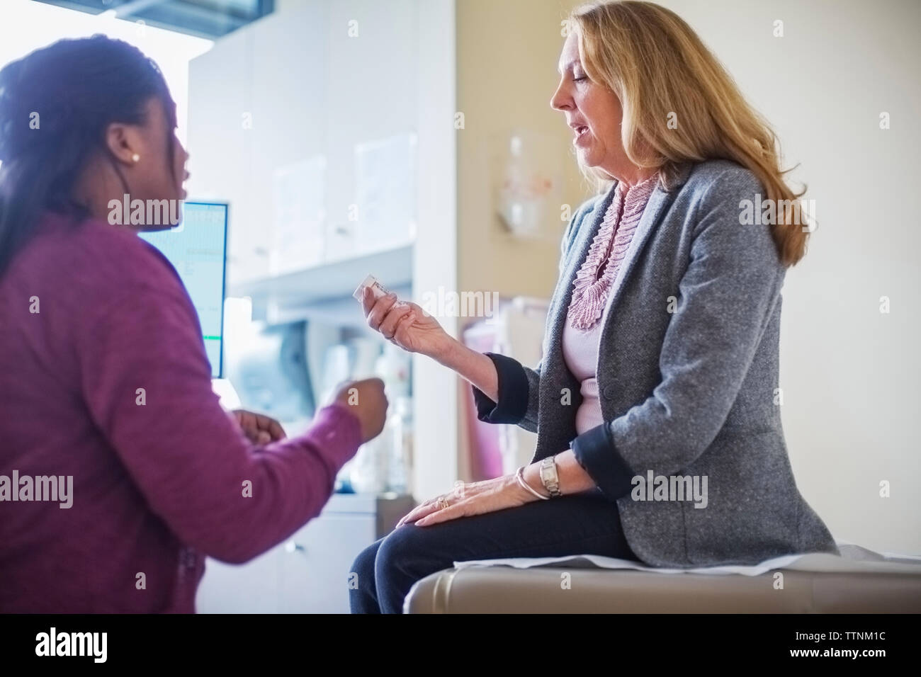 Paziente che mostra la prescrizione di medicine per il medico donna nella sala medica Foto Stock