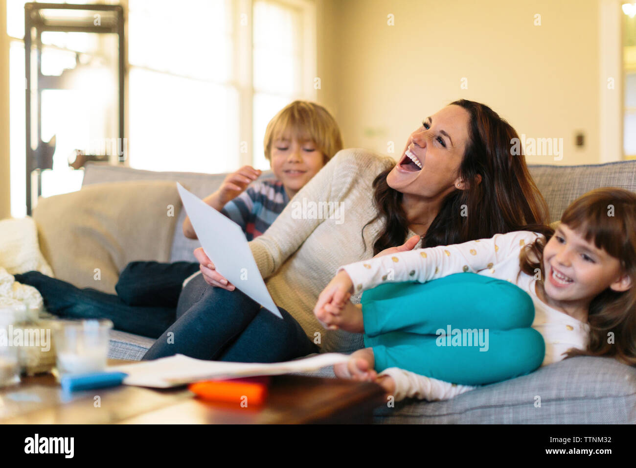 Giocoso madre con bambini seduti sul divano di casa Foto Stock