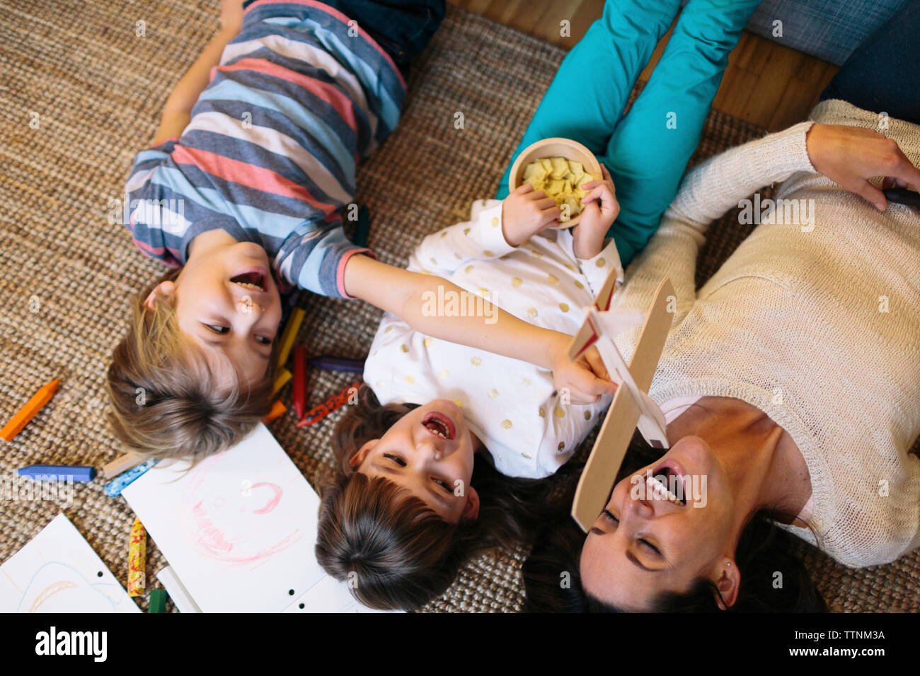 Vista aerea di bambini allegri con la madre giacente su un tappeto a casa Foto Stock