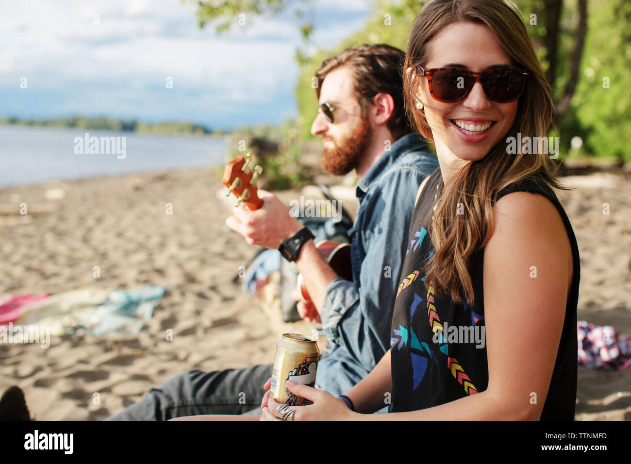 Donna sorridente seduto con un amico a giocare ukulele Foto Stock