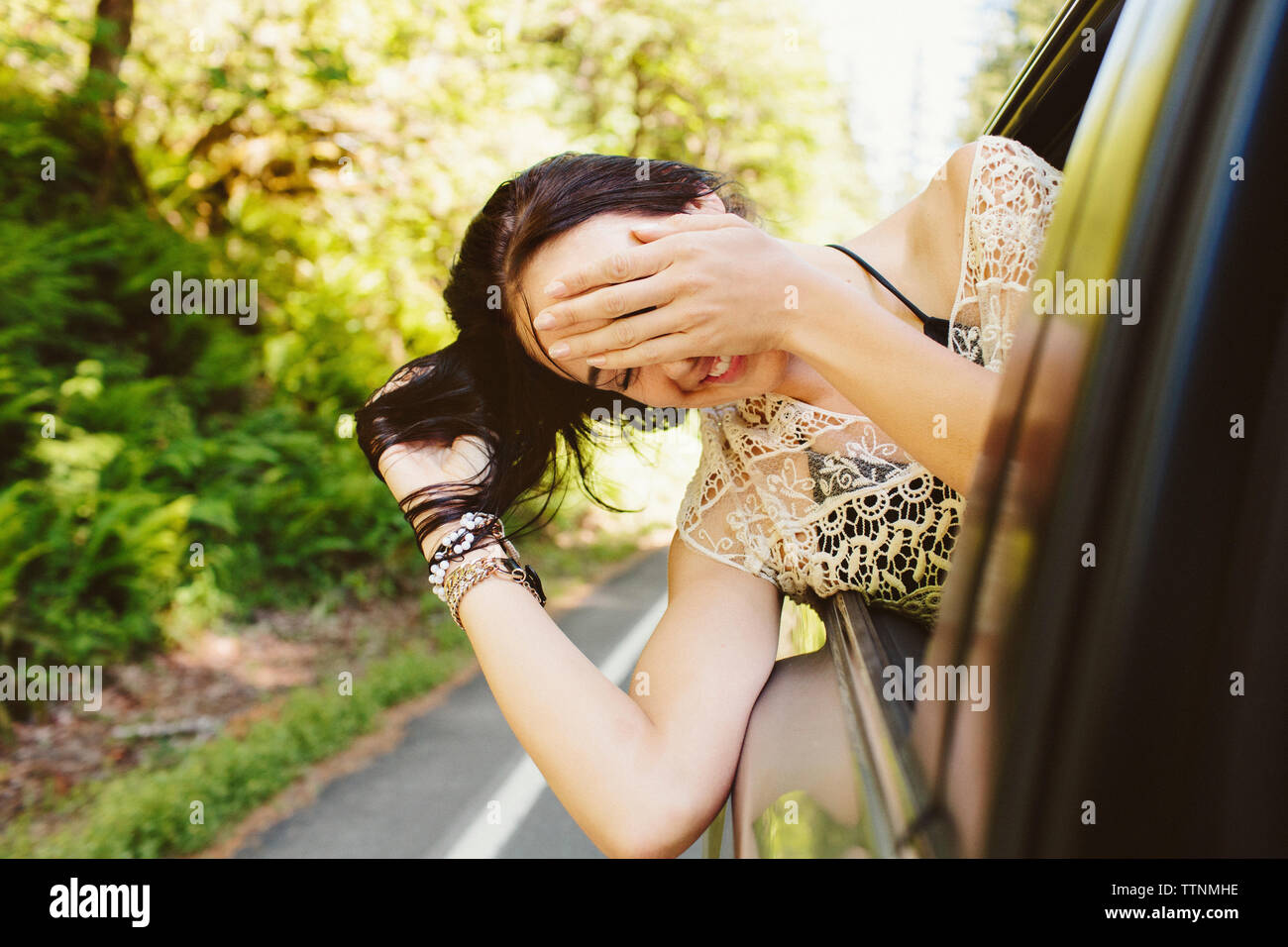 Donna felice spiata attraverso la finestra mentre si viaggia in auto Foto Stock