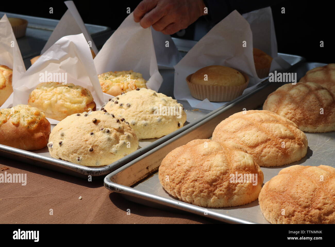 Visualizzare ofJapanese pane dolce su vassoi da forno con la mano toccare carta oleata tra cui il pane di melone con disegno a griglia Foto Stock