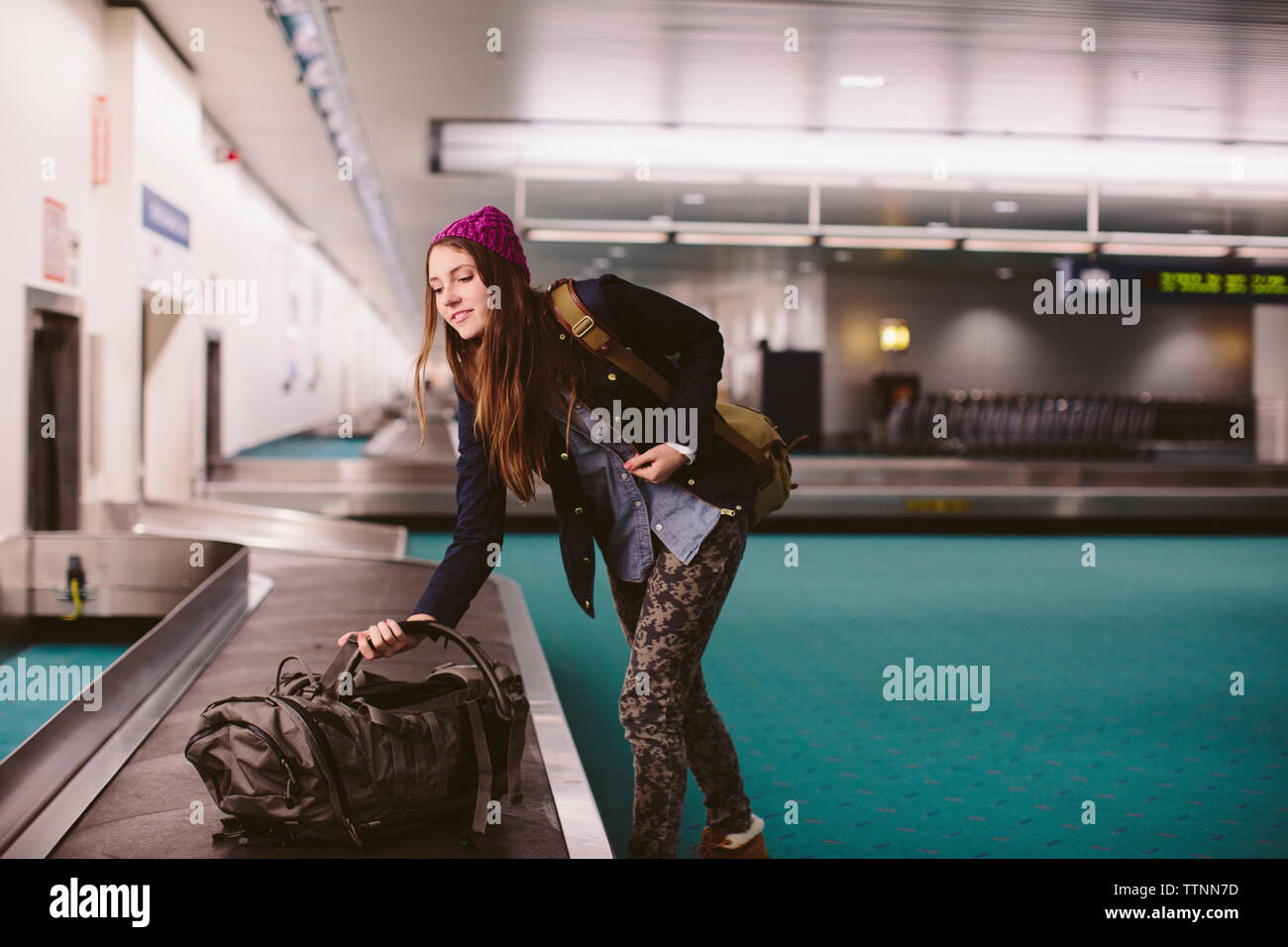 Donna portare i bagagli dal reclamo bagagli in aeroporto Foto Stock