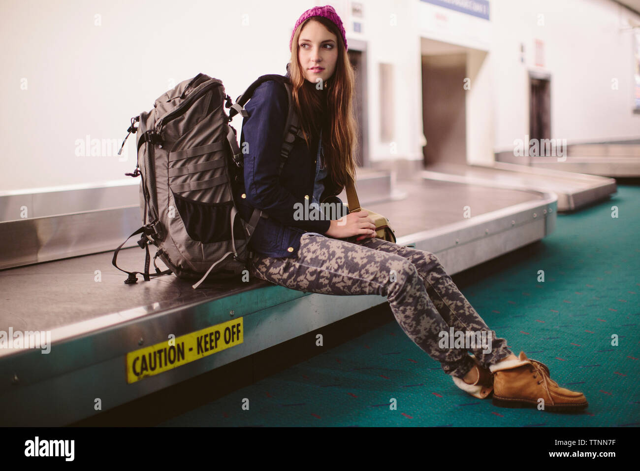Donna con bagagli seduti sul reclamo bagagli in aeroporto Foto Stock