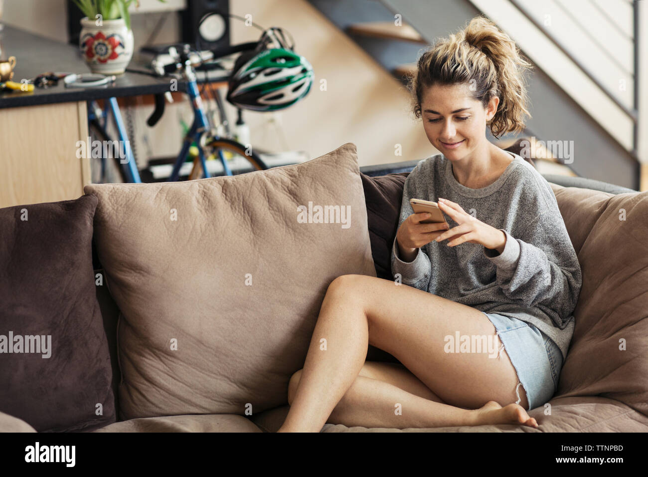 Donna di messaggistica di testo comodamente seduti sul divano di casa Foto Stock