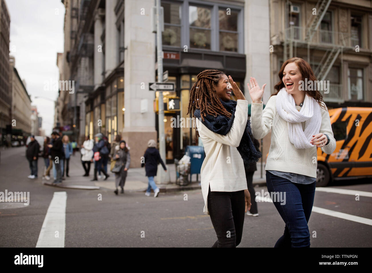 Happy amici di sesso femminile dando alta cinque mentre si cammina sulla strada Foto Stock