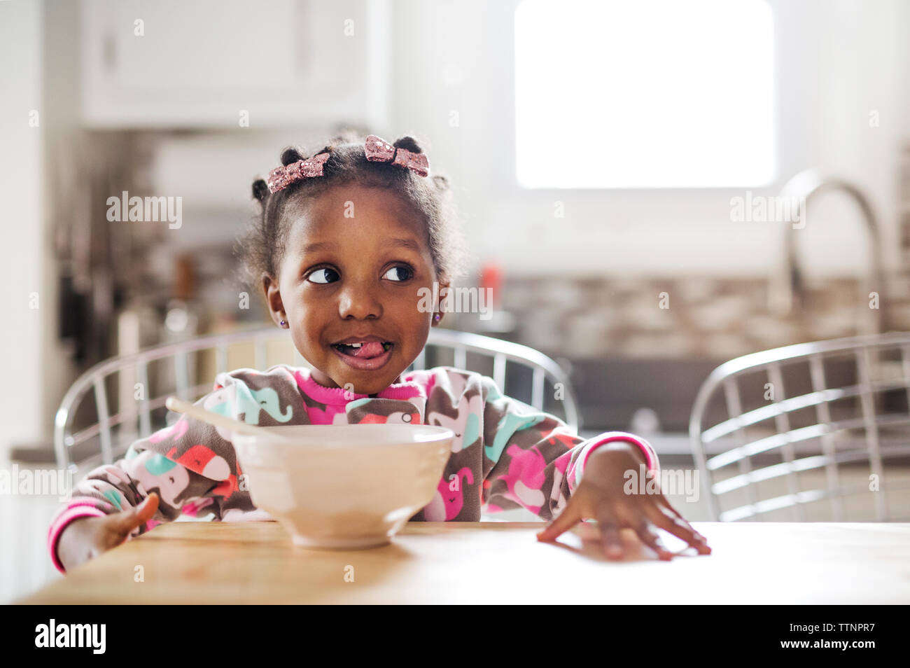 Ragazza carina rendendo faccia pur avendo prima colazione in cucina Foto Stock