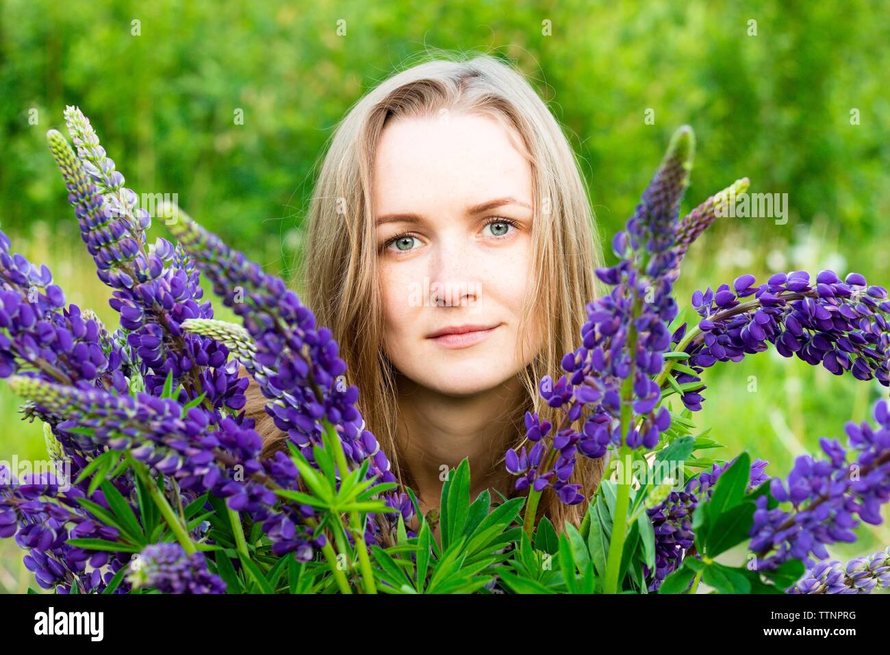 Bella e giovane ragazza tra i bellissimi fiori di lupini. Essa gode del momento di essere tra un mazzo di fiori di tonalità di viola. Foto Stock