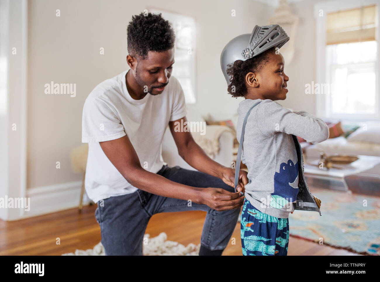 Padre vestire il ragazzo come cavaliere in costume di armor a casa Foto Stock