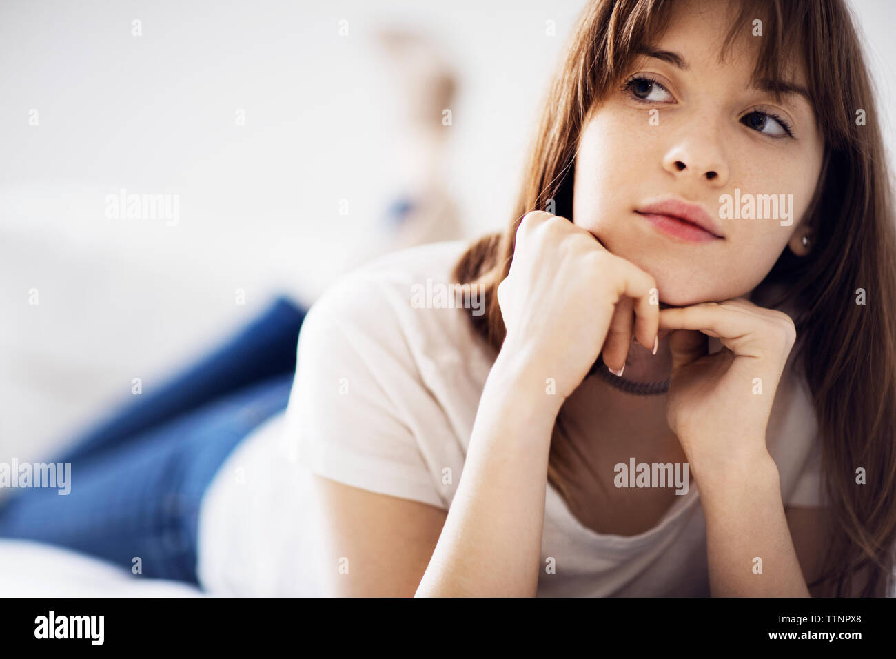 Considerato giovane donna sdraiata sul letto di casa Foto Stock