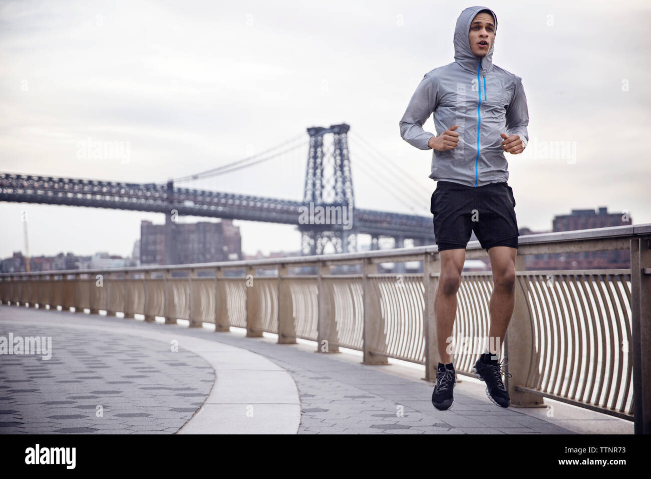 Determinato atleta maschio in esecuzione sul sentiero con Williamsburg Bridge in background Foto Stock