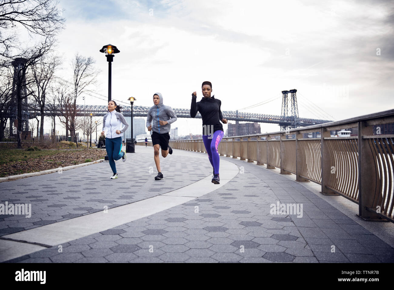 Dedicato multi-etnico atleti in esecuzione sul sentiero con Williamsburg Bridge in background Foto Stock