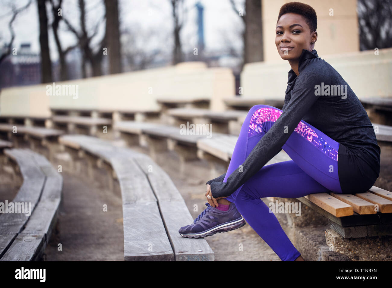 Premurosa donna che indossa calzatura sportiva mentre è seduto alla stadium Foto Stock