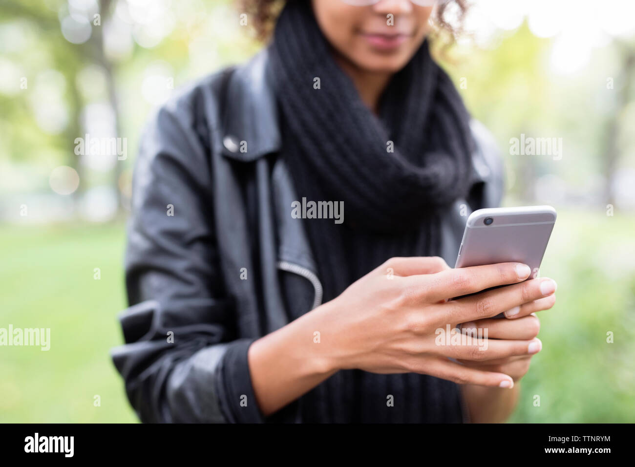 Sezione mediana della donna utilizzando il telefono cellulare in posizione di parcheggio Foto Stock