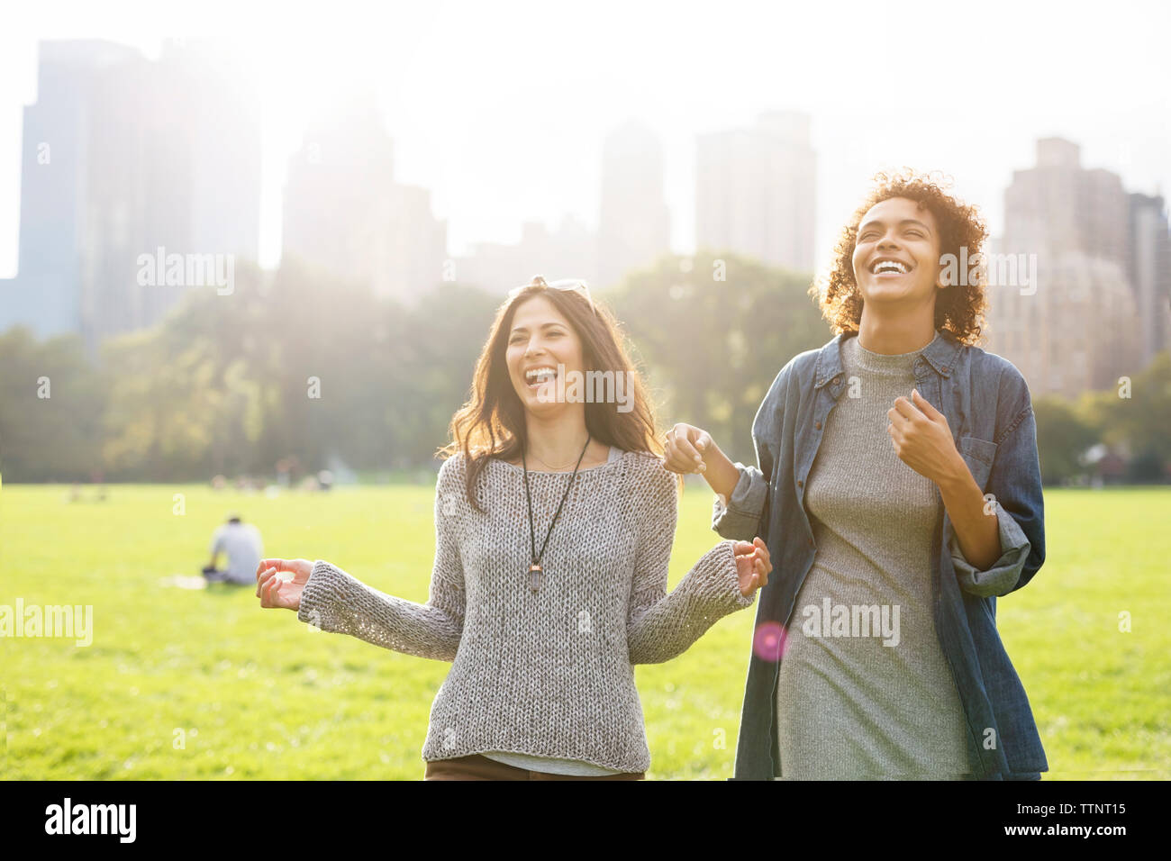 Gli amici di ridere mentre si sta in piedi sul campo al park Foto Stock