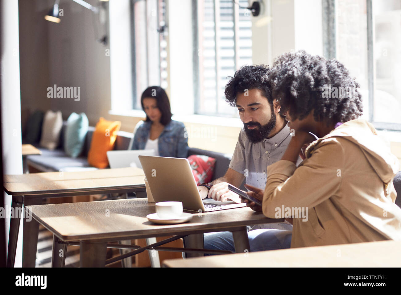 uomini d'affari che lavorano su un computer portatile con una collega seduta in background Foto Stock