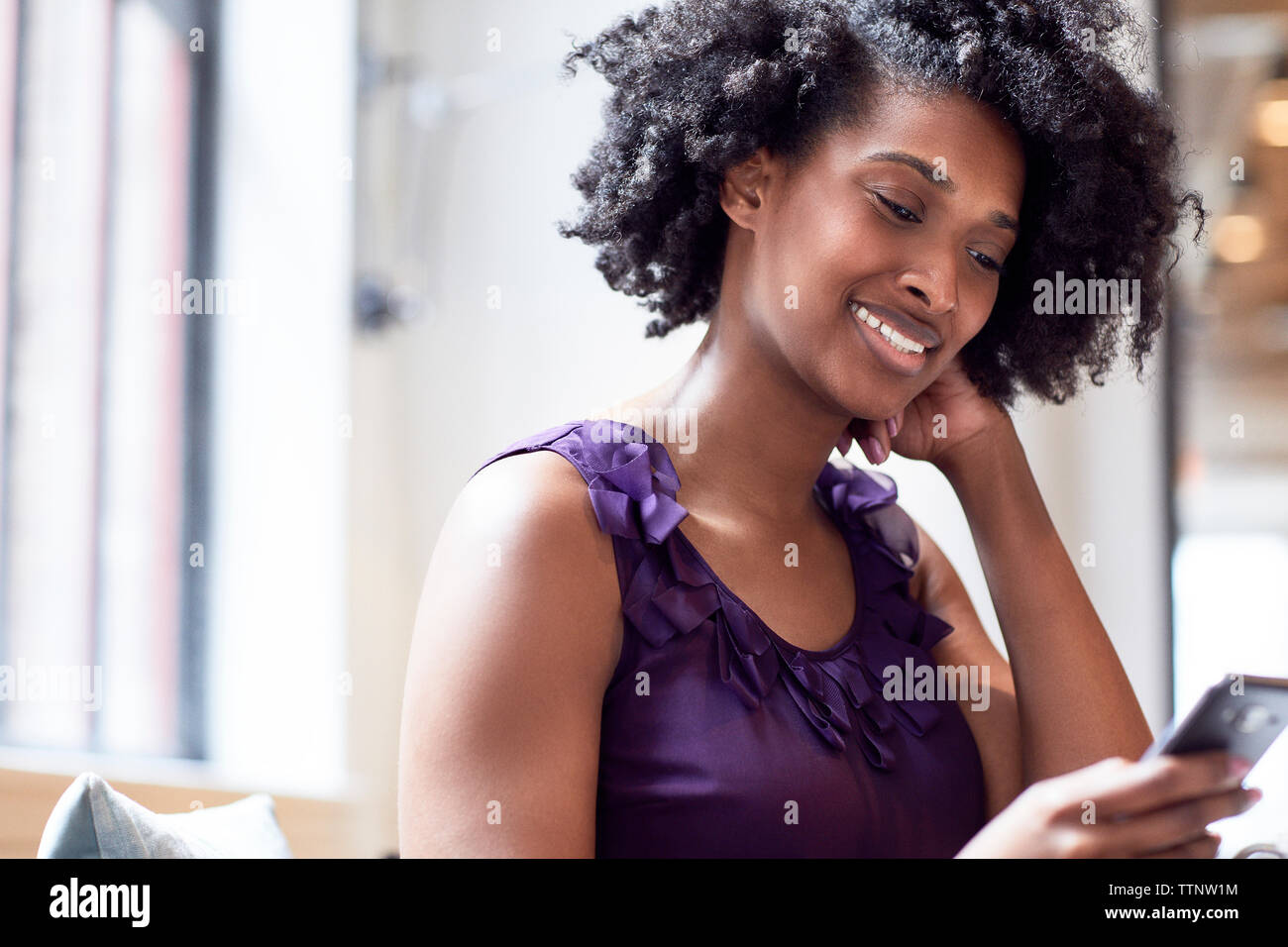 Felice imprenditrice utilizzando smart phone in office Foto Stock