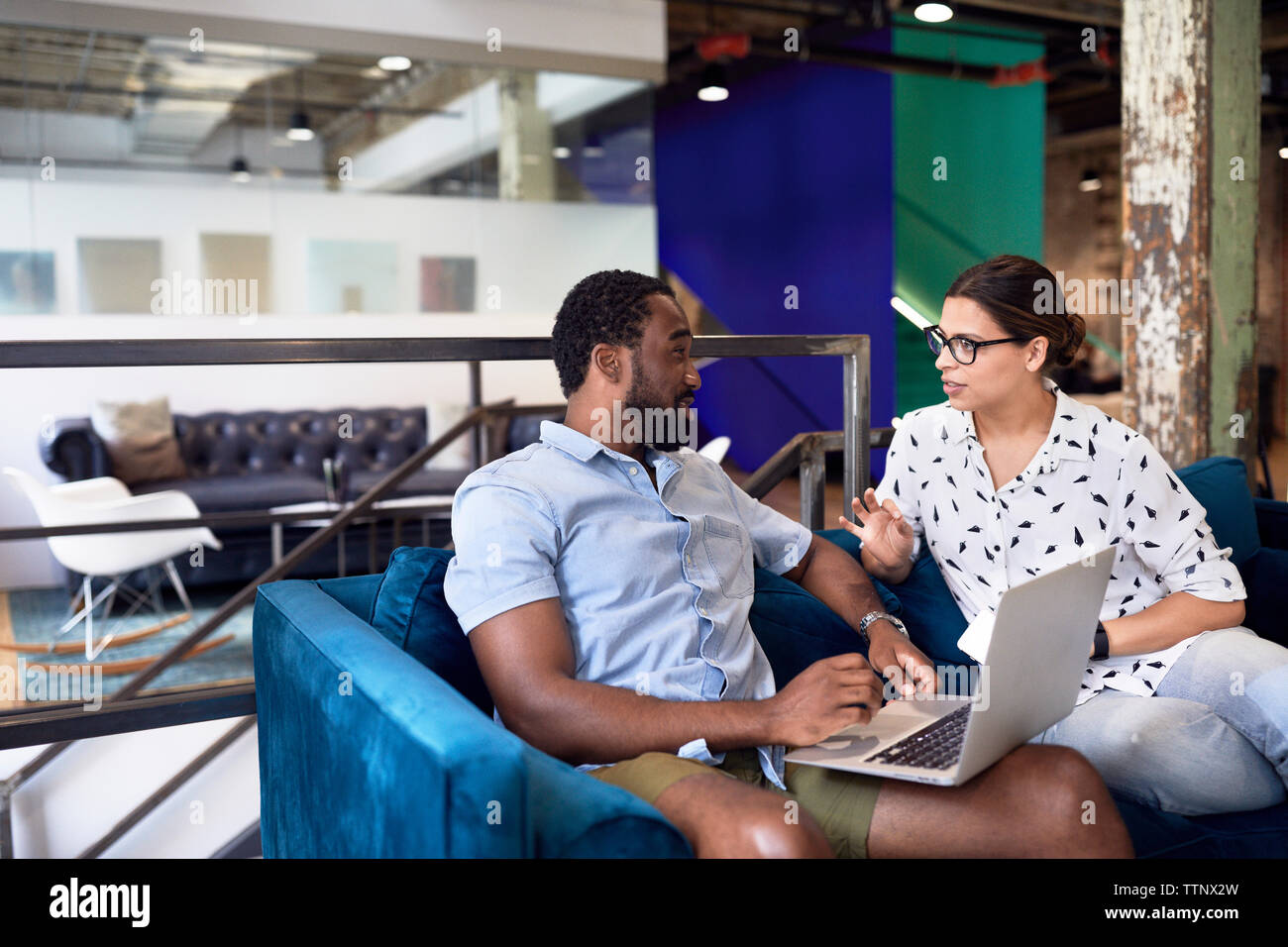 Multi-etnico business persone per discutere su computer portatile mentre è seduto sul divano presso il creative office Foto Stock