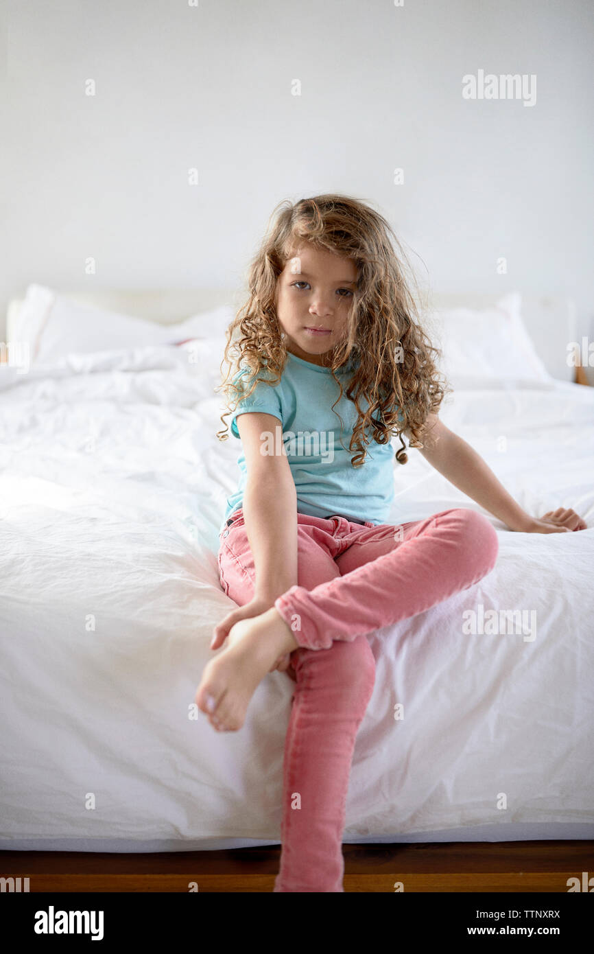 Ritratto di ragazza seduta sul letto di casa Foto Stock