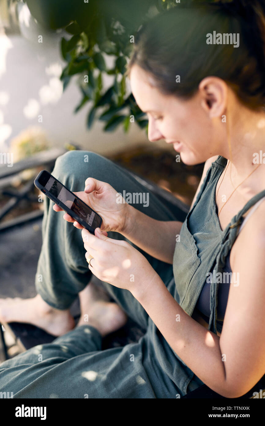 Elevato angolo di visione della donna che utilizza internet sul telefono nel cortile posteriore Foto Stock