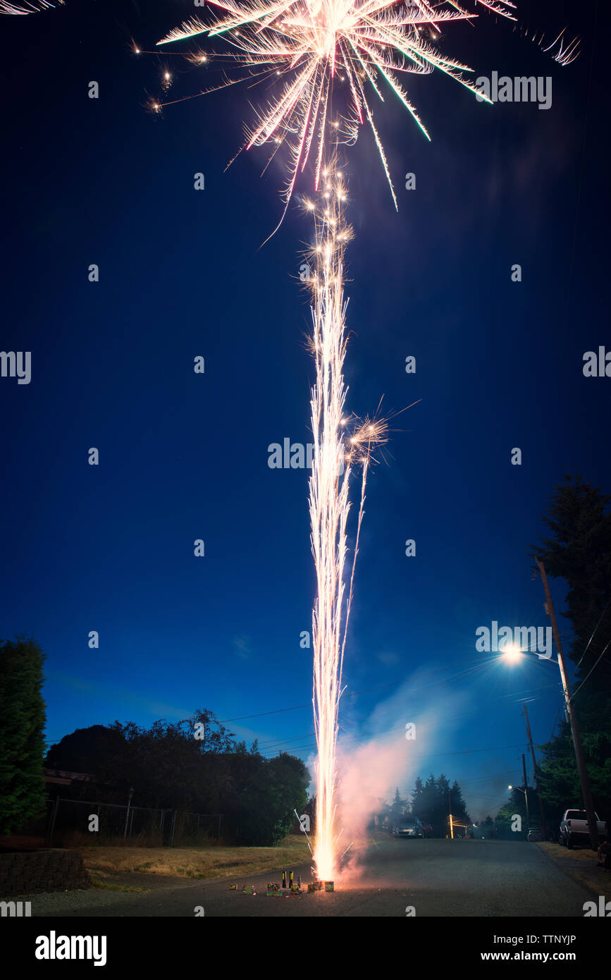 Fuochi d'artificio esplodono in strada contro il cielo blu Foto Stock